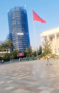 um homem com uma bandeira vermelha em frente a um edifício alto em SweetHome, a Little Paradise in Center of Tirana em Tirana