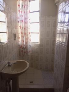 baño blanco con lavabo y ventana en Hotel el LUCERO, en Oruro