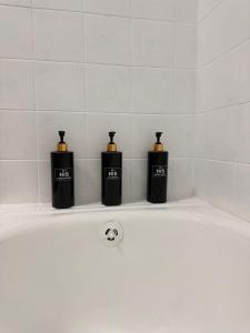 three black bottles sitting on the edge of a bath tub at Cuatro Vientos in Vigo