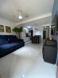 ein Wohnzimmer mit einem blauen Sofa und einer Küche in der Unterkunft Casa temporada Cabo Frio in Cabo Frio