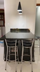 a kitchen counter with three stools around it at Casa temporada Cabo Frio in Cabo Frio