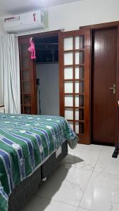 ein Schlafzimmer mit einem Bett mit einer grünen und weißen Decke in der Unterkunft Casa temporada Cabo Frio in Cabo Frio