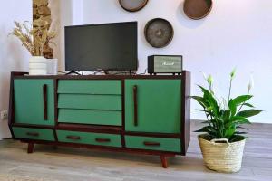 a green dresser with a television on top of it at Sopas e Descanso in Grândola