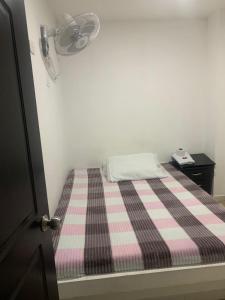 un piccolo letto con coperta a scacchi rosa e nera di Hotel La Fresa a Pereira