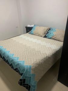 Una cama con edredón en un dormitorio en Hotel La Fresa en Pereira