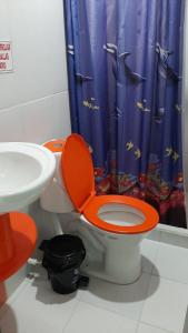 bagno con servizi igienici e coperchio arancione accanto a un lavandino di Hotel La Fresa a Pereira