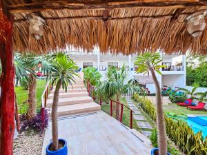 a pathway with palm trees and a thatched roof at Mayan Majesty Boutique Hotel in Valladolid