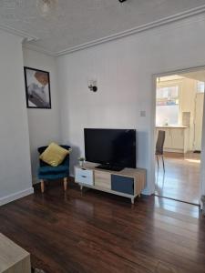 a living room with a flat screen tv and a chair at Cosy 3 Bedroom House in Beeston, Leeds, LS11 7JP in Beeston