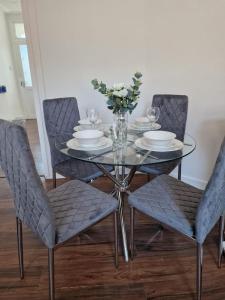 a dining room table with chairs and a glass table with plates at Cosy 3 Bedroom House in Beeston, Leeds, LS11 7JP in Beeston