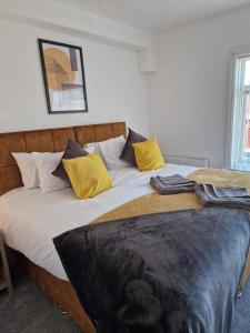 a bedroom with a large bed with yellow pillows at Cosy 3 Bedroom House in Beeston, Leeds, LS11 7JP in Beeston