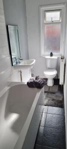 Baño blanco con lavabo y aseo en Cosy 3 Bedroom House in Beeston, Leeds, LS11 7JP, en Beeston