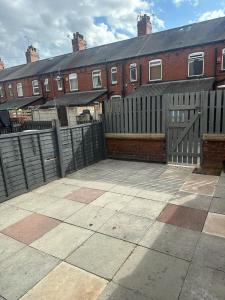 a fence in front of a brick building at Cosy 3 Bedroom House in Beeston, Leeds, LS11 7JP in Beeston