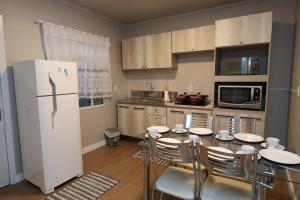 a kitchen with a table with chairs and a refrigerator at Casa no Centro de Concórdia - SC in Concordia
