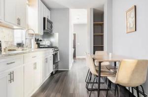 een keuken met witte kasten en een tafel en stoelen bij Cozy House 20 min to NYC up to 8 People in Fairview
