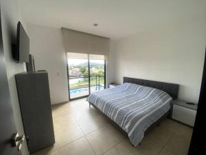 een slaapkamer met een bed en een groot raam bij Tenis, Golf y Alberca, hermoso Condo para descanso in Emiliano Zapata