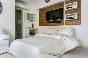 Schlafzimmer mit einem weißen Bett und einem TV an der Wand in der Unterkunft Apto c/ sacada no Open Shopping Jurerê IBI307 in Florianópolis