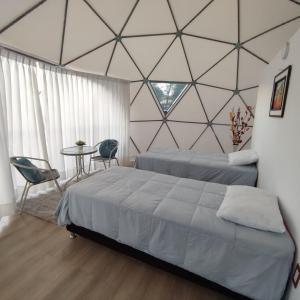 a bedroom with two beds and a table and a window at Sky Lodge Domes Cusco in Cusco