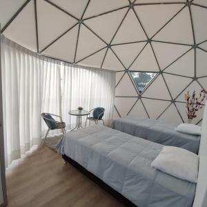 a bedroom with two beds and a table in a glass wall at Sky Lodge Domes Cusco in Cusco