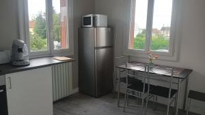 a kitchen with a stainless steel refrigerator and a table at Cassiopée avec jardin in Fleury-les-Aubrais