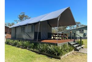 a tent with a wooden deck in a yard at Discovery Parks - Narooma Beach in Narooma