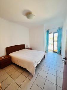 una camera con letto bianco e tende blu di Apartamento golf-mar a Vilamoura