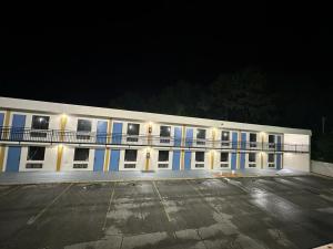 a large white building with a parking lot at night at Lanett Inn in Lanett