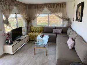 uma sala de estar com um sofá e uma televisão em Mellalyène em Tétouan