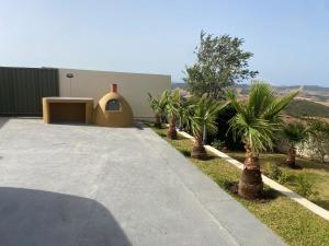 a house with a driveway with palm trees in front of it at Mellalyène in Tétouan