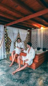 two people in white robes sitting on a bed at Bio Rio Hotel in San Jerónimo