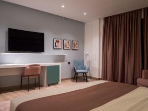 a hotel room with a bed and a tv and chairs at HOTEL HIBA in Nouakchott