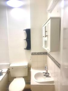 a bathroom with a white toilet and a sink at Large self-contained cozy studio in London