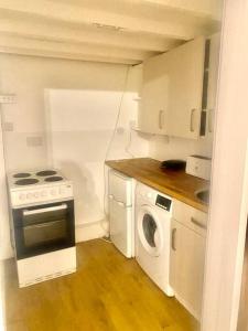 a small kitchen with a stove and a washing machine at Large self-contained cozy studio in London