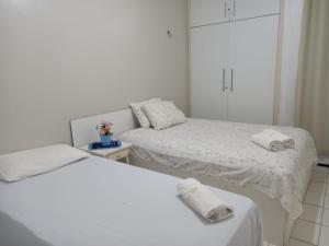 Dos camas en una habitación blanca con toallas. en Residencial André Reis, en Fortaleza