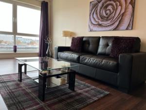 a living room with a leather couch and a glass table at AB11 Apartments - Portland Street in Aberdeen