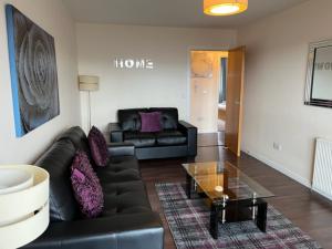 a living room with a black couch and a glass table at AB11 Apartments - Portland Street in Aberdeen