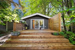 ein Haus mit einer Holzterrasse im Wald in der Unterkunft Sunwolf Riverside Cabins in Brackendale