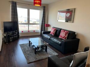 a living room with a black leather couch and a coffee table at AB11 Apartments - Portland Street in Aberdeen