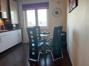a kitchen with a table and chairs and a clock on the wall at AB11 Apartments - Portland Street in Aberdeen