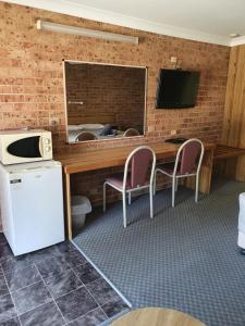 una camera con scrivania, TV, tavolo e sedie di Alyn Motel a Gunnedah