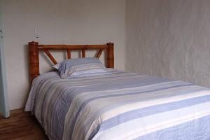 a bed with a wooden frame in a bedroom at Pinar del Rio Eco Habitación Madera in San Agustín