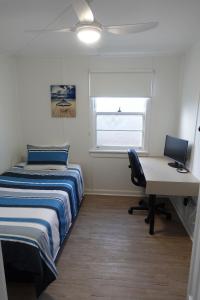 a bedroom with a bed and a desk and a computer at Christina Cottage in South West Rocks