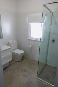 a bathroom with a toilet and a glass shower at Christina Cottage in South West Rocks