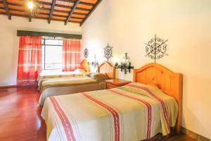 a bedroom with three beds in a room at Hotel Pie de la Sierra in Uruapan del Progreso
