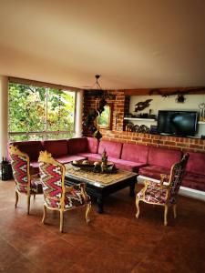 sala de estar con sofá rojo y 2 sillas en Finca con forma de castillo y piscina en Sopetrán en Sopetran