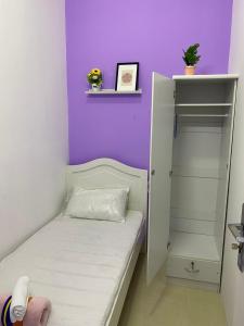 Dormitorio pequeño con cama y pared púrpura en Single Partition Room in Al Barsha 1 Near Mashreq Metro, en Dubái