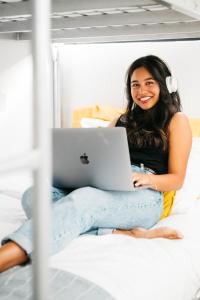 a woman sitting on a bed with a laptop at The Lansdowne Hotel in Sydney