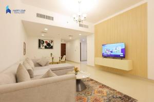 a living room with a couch and a tv on a wall at Spacious 2BR near MOE - 2 Min Drive in Dubai