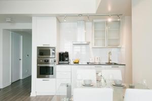 una cucina con armadi bianchi e tavolo con sedie di Beautiful Luxurious Modern Condo With Breathtaking Views a Toronto