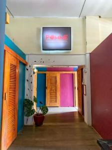 un pasillo con TV en la pared y una planta en Pomme Hostel Restaurant & Bar - Private Sleeping Cabins en Battambang