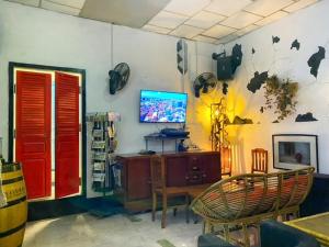 um quarto com uma mesa e uma televisão na parede em Pomme Hostel Restaurant & Bar - Private Sleeping Cabins em Battambang